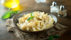 Imagem de um prato com uma porção de macarrão penne ao molho de queijo.